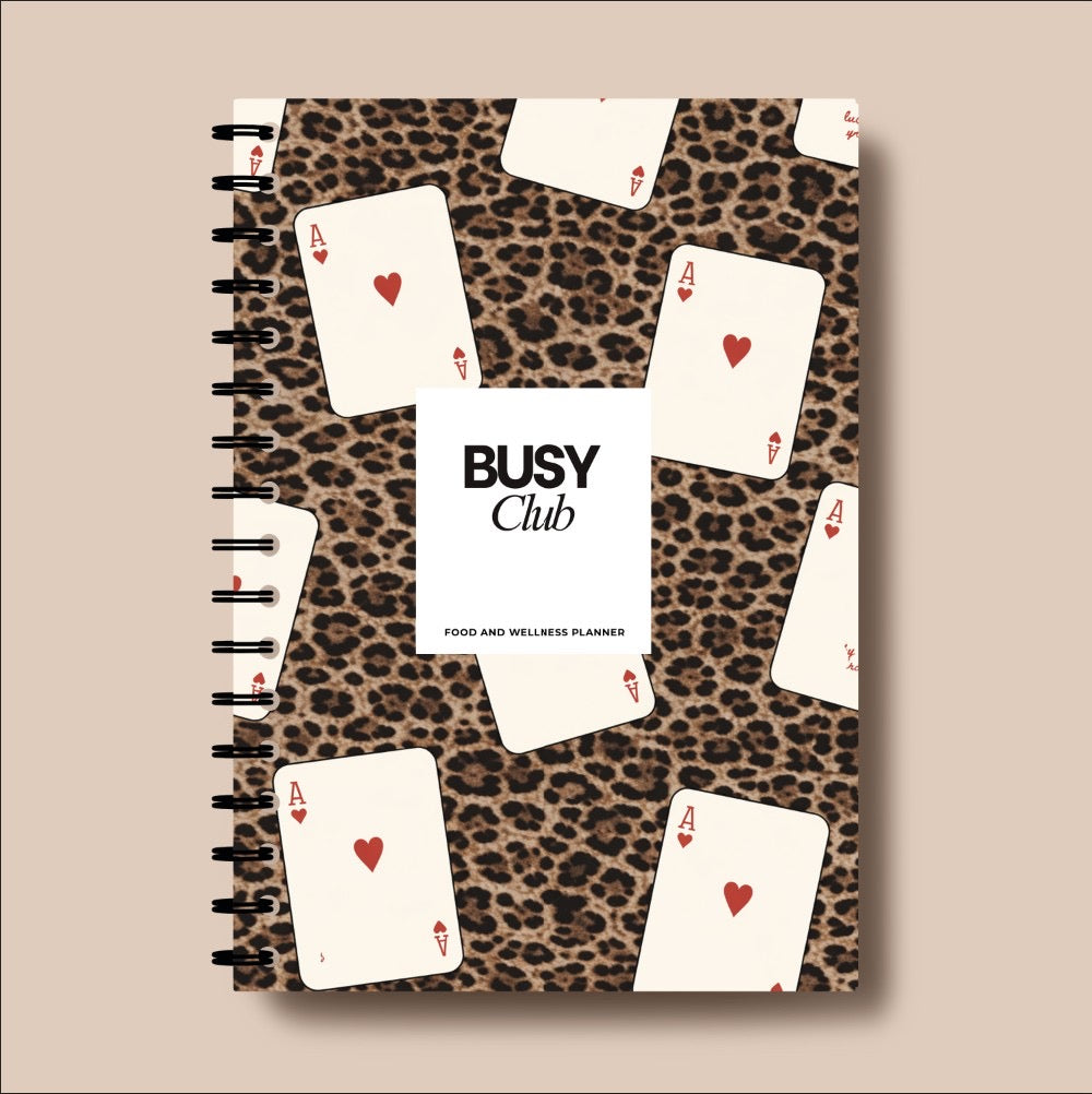 Notebook with leopard print cover featuring playing cards and 'Busy Club' branding.