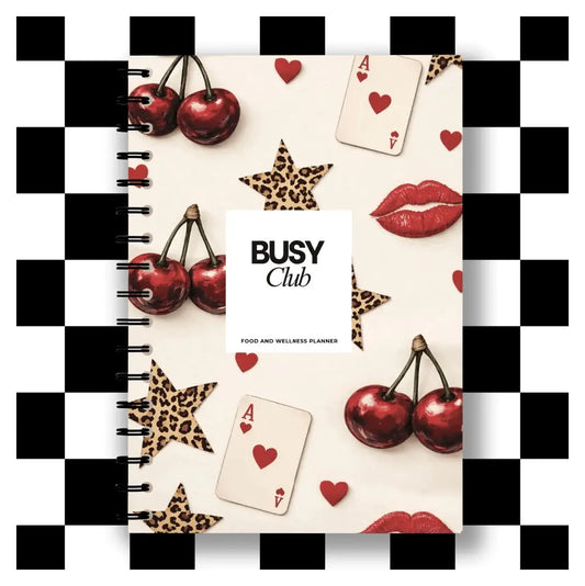 Notebook with decorative elements like cherries, cards, and stars on a checkered border