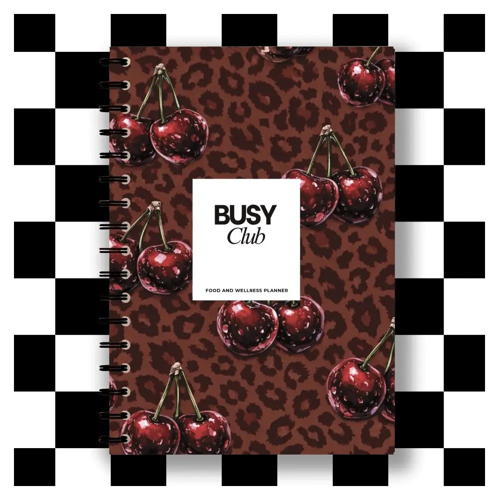Notebook with cherry design and 'BUSY Club' branding on a checkered background