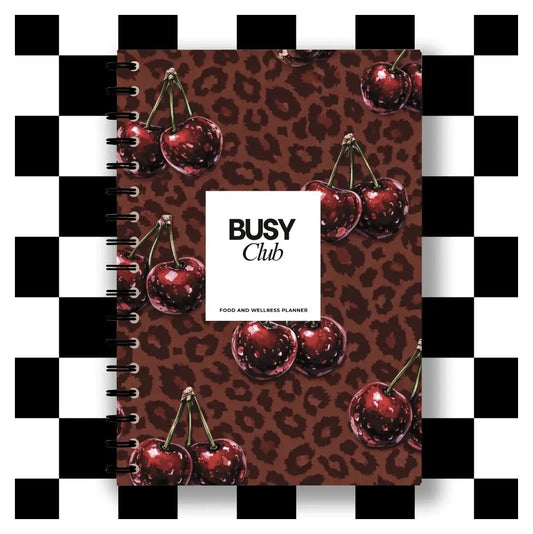 Notebook with cherry design and 'BUSY Club' branding on a checkered background