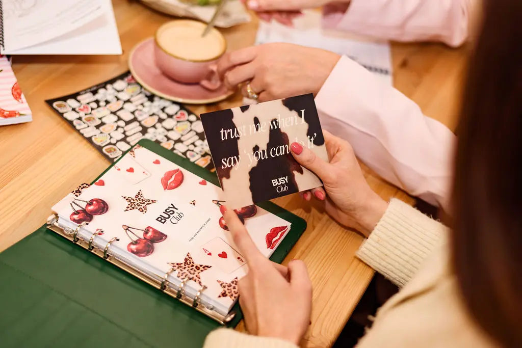 Person holding a card with a design of a woman smoking a cigarette, surrounded by other cards on a table.
