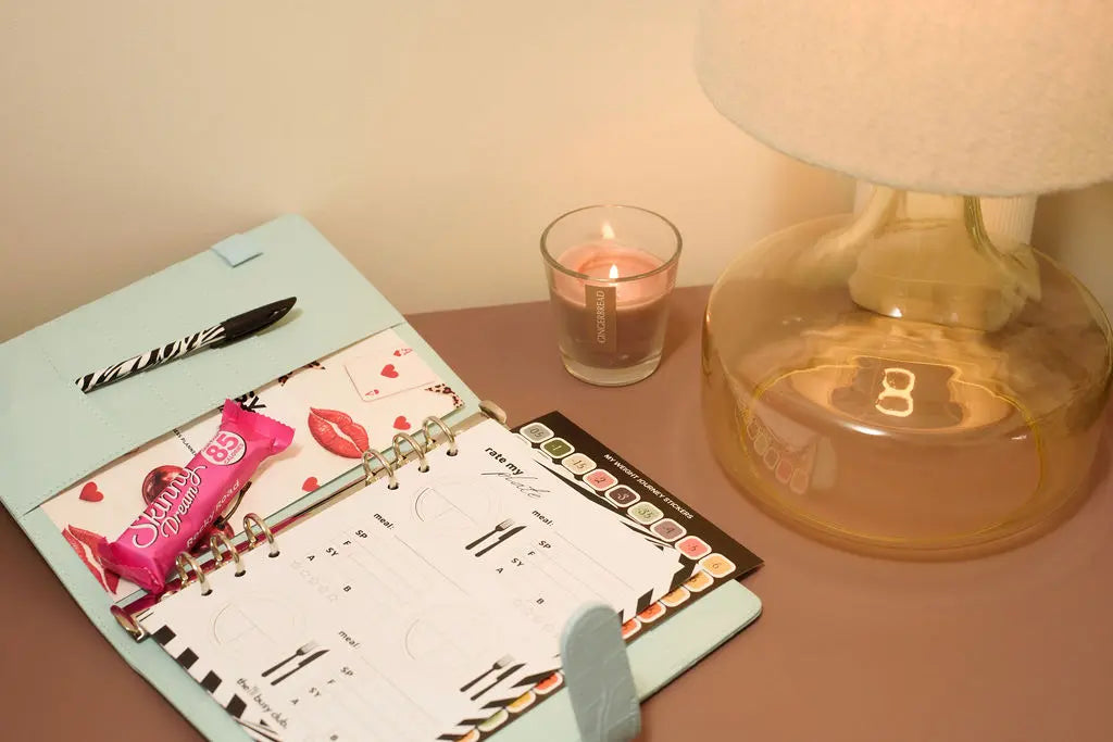 Desk with planner, candy, pen, candle, and lamp