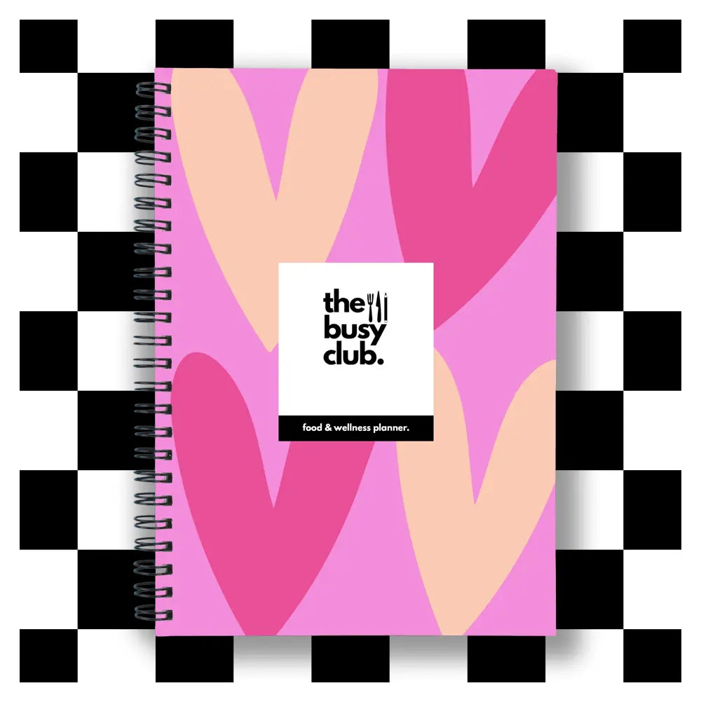 Notebook with abstract heart design and 'the busy club' branding on a checkered background