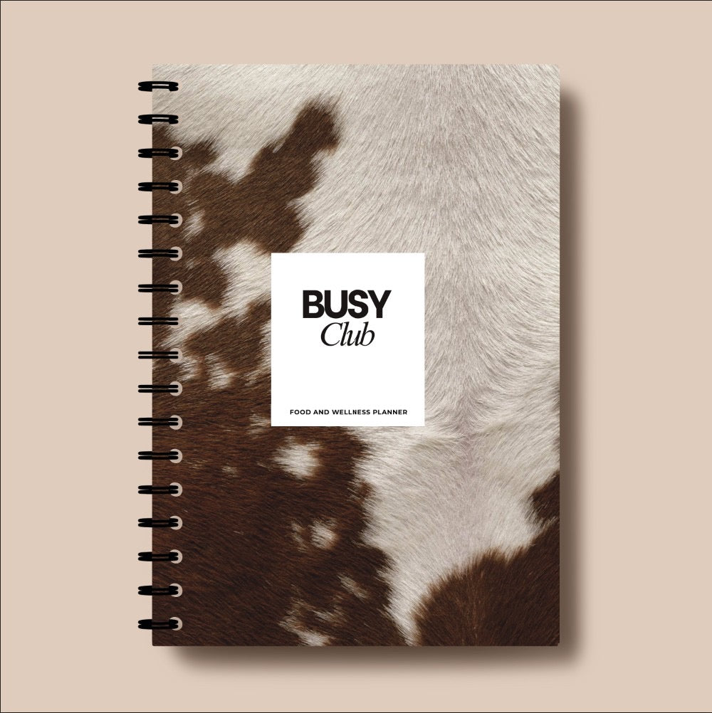 Notebook with cowhide texture cover and 'Busy Club' label on a beige background