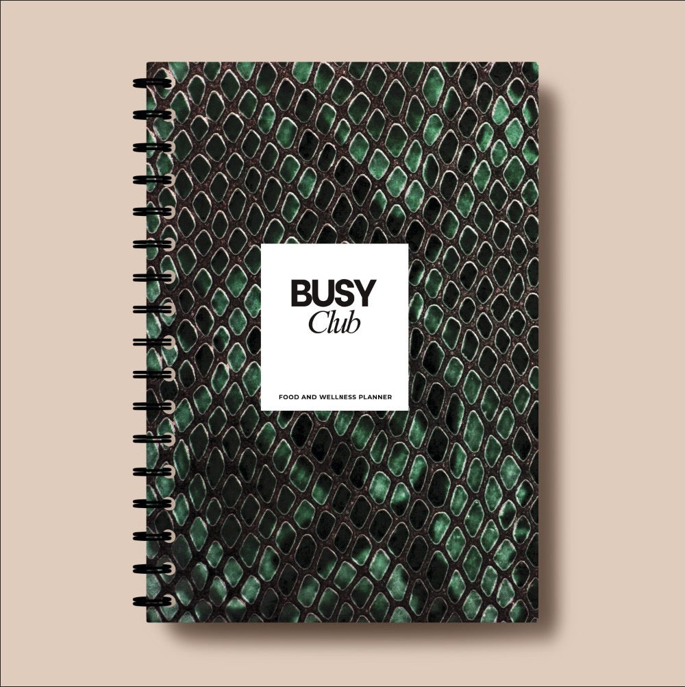 Notebook with green snake skin pattern and 'BUSY Club' label on a beige background