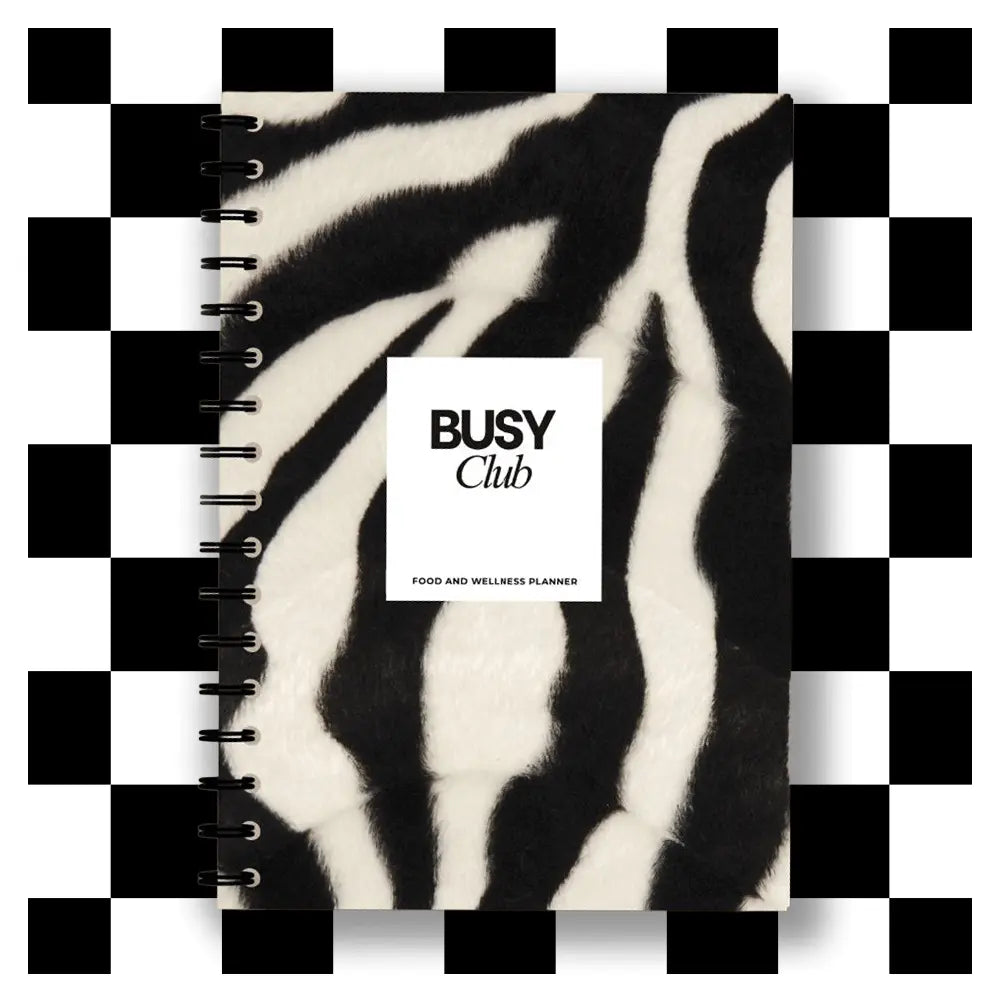 Notebook with zebra print cover and 'Busy Club' branding on a checkered background