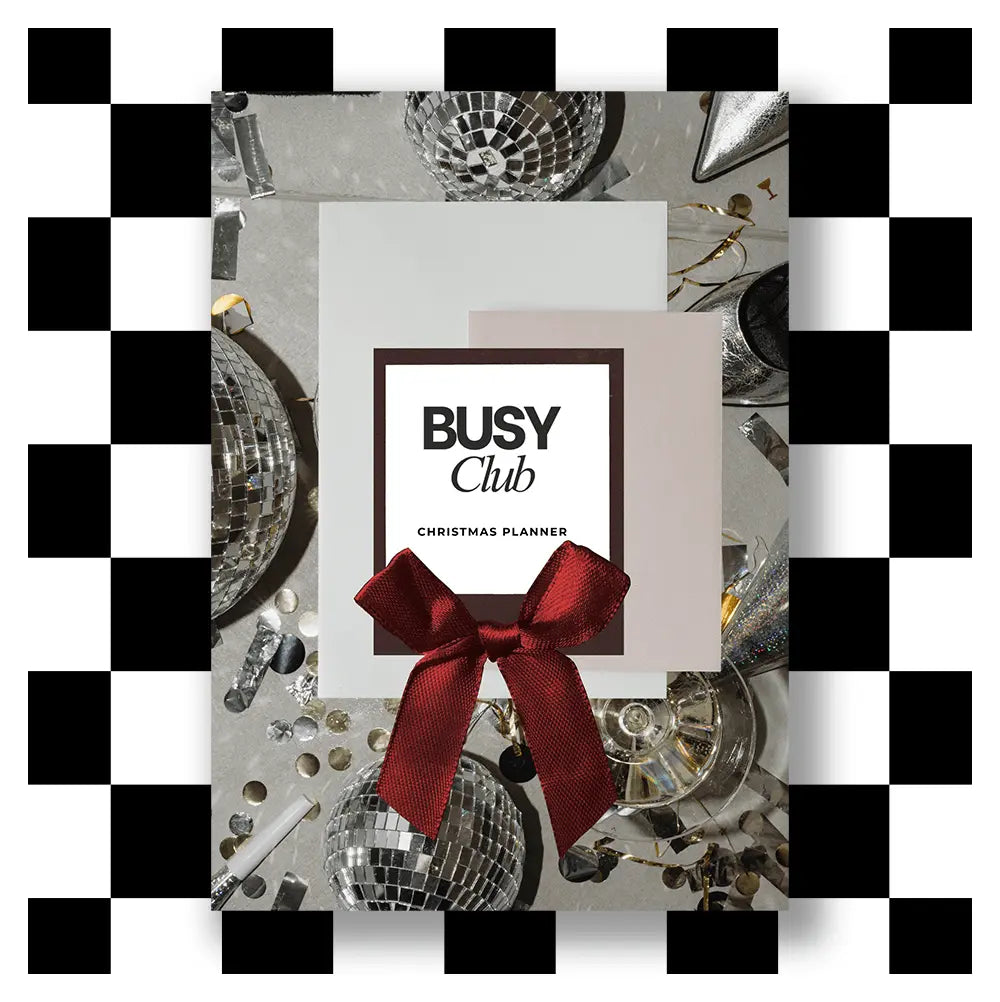 Front cover for the 'Busy Club Christmas Planner' with a red bow, surrounded by disco ball decorations on a black and white checkered background.